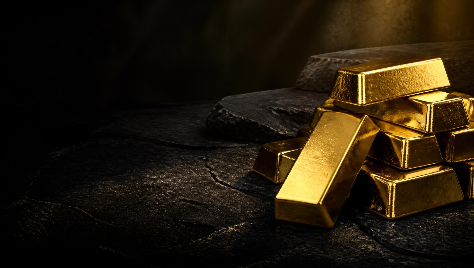 Gold bullion bars on dark stone under warm lighting