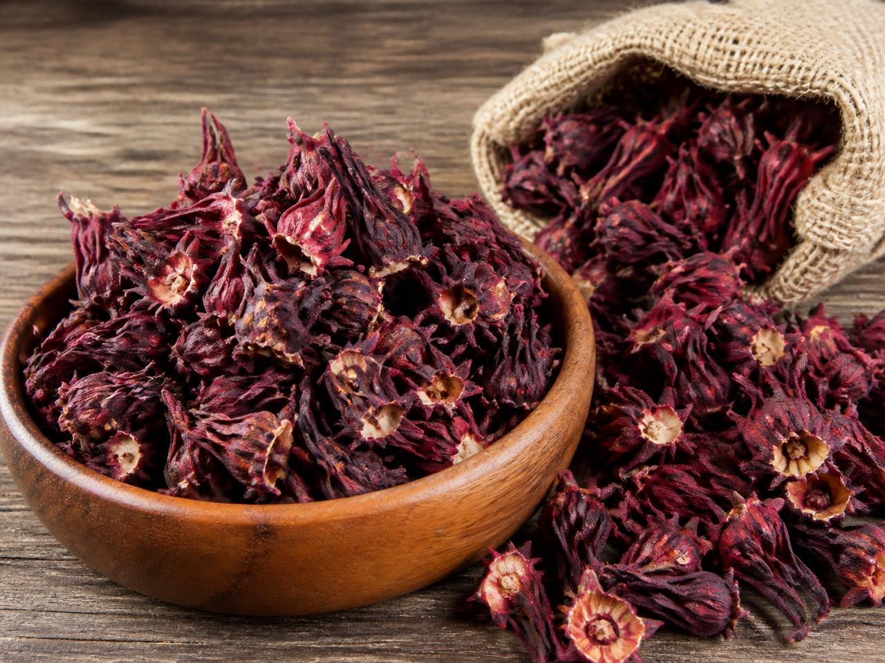 Dried red hibiscus calyces in a wooden bowl